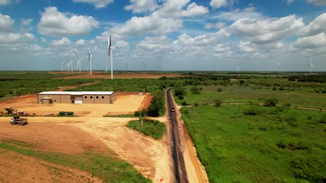 Work-truck-driving-down-dirt-road-by-a-wind-farm