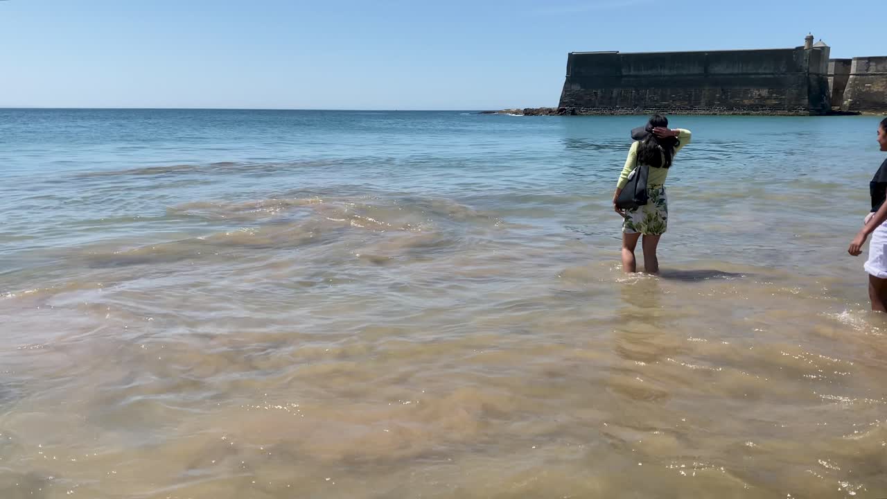 매력적인 여성이 oeiras 해변에서 물에 발을 담그고, 매우 세련된 드레스를 입고  ⁇ 은 날, 포르투갈 관광