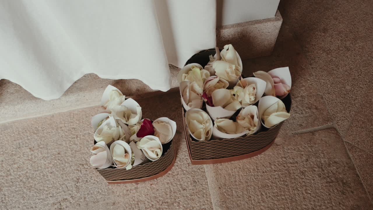 Small wicker baskets filled with white flower petals placed on stone floor for wedding ritual