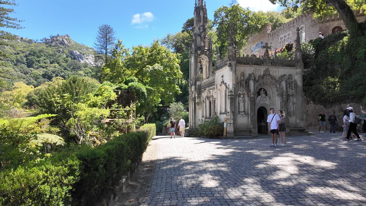 Gothic-style palace surrounded by lush greenery and tourists in Sintra, Portugal on a sunny day