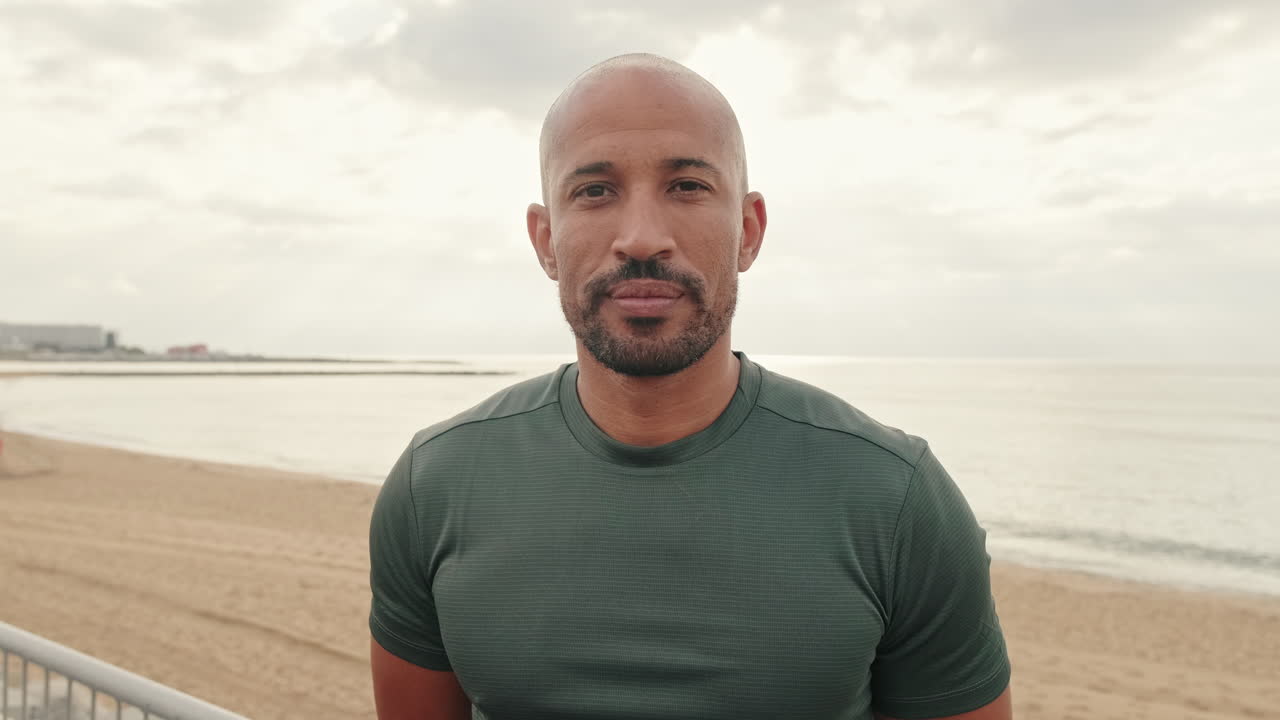 Confident Bald Man with Beard on Beach Looking at Camera