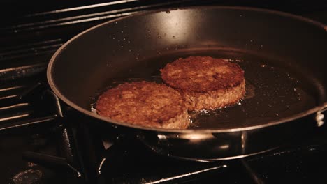 plantbased burgers gently frying in pan with oil on gas stove