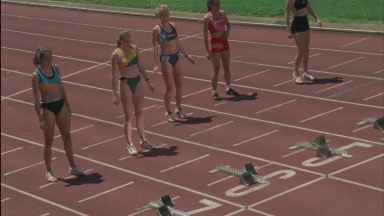 cinco chicas se acercan a los bloques y se preparan para correr