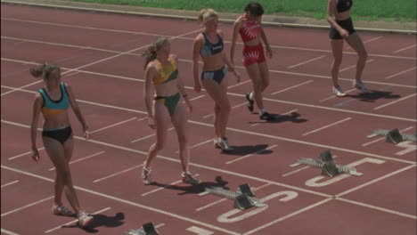 cinco chicas se acercan a los bloques y se preparan para correr