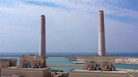 aerial view of a large coastal power plant with tall smokestacks