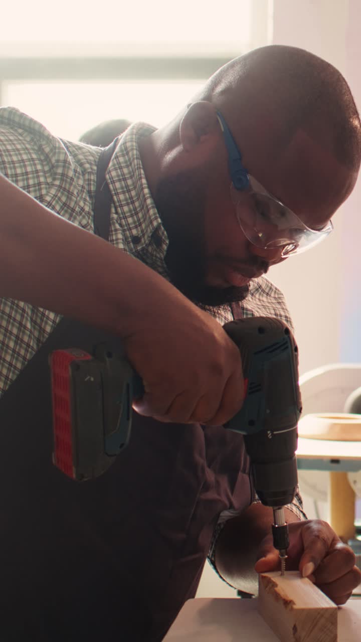 Focused Carpenter Drilling into Wood with Power Drill in Workshop