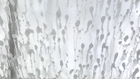 driver's side window of car being sprayed with soap at an automatic car wash.
