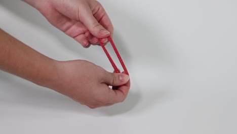 hands manipulating a red hair tie