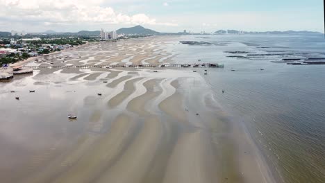 barcos arrastrados a tierra en las planicies de marea en la playa de bang saen en chonburi, tailandia - drone aéreo