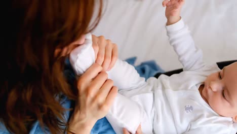 madre joven sosteniendo al bebé en el regazo y jugando en la cama en el dormitorio 4k
