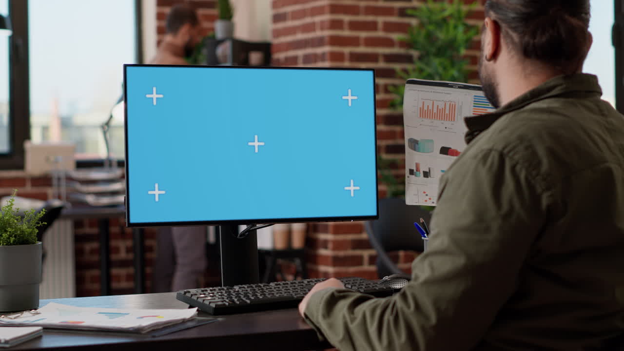 Startup employee looking at greenscreen template on monitor