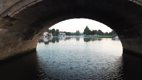 impressive drone shot of henley on thames, flying through the bridge at sunrise