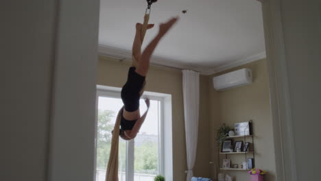 joven realizando una rutina de seda aérea en casa