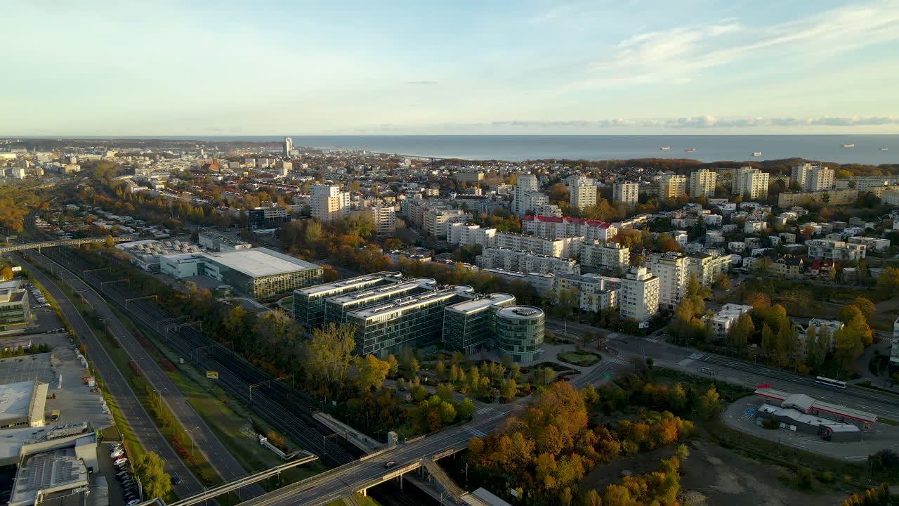 Ilmakuva Pommerin teknologiapuiston modernista rakennuksesta, asuinalueen kortteleista ja Itämerestä taustalla auringonnousun aikaan Puolassa.