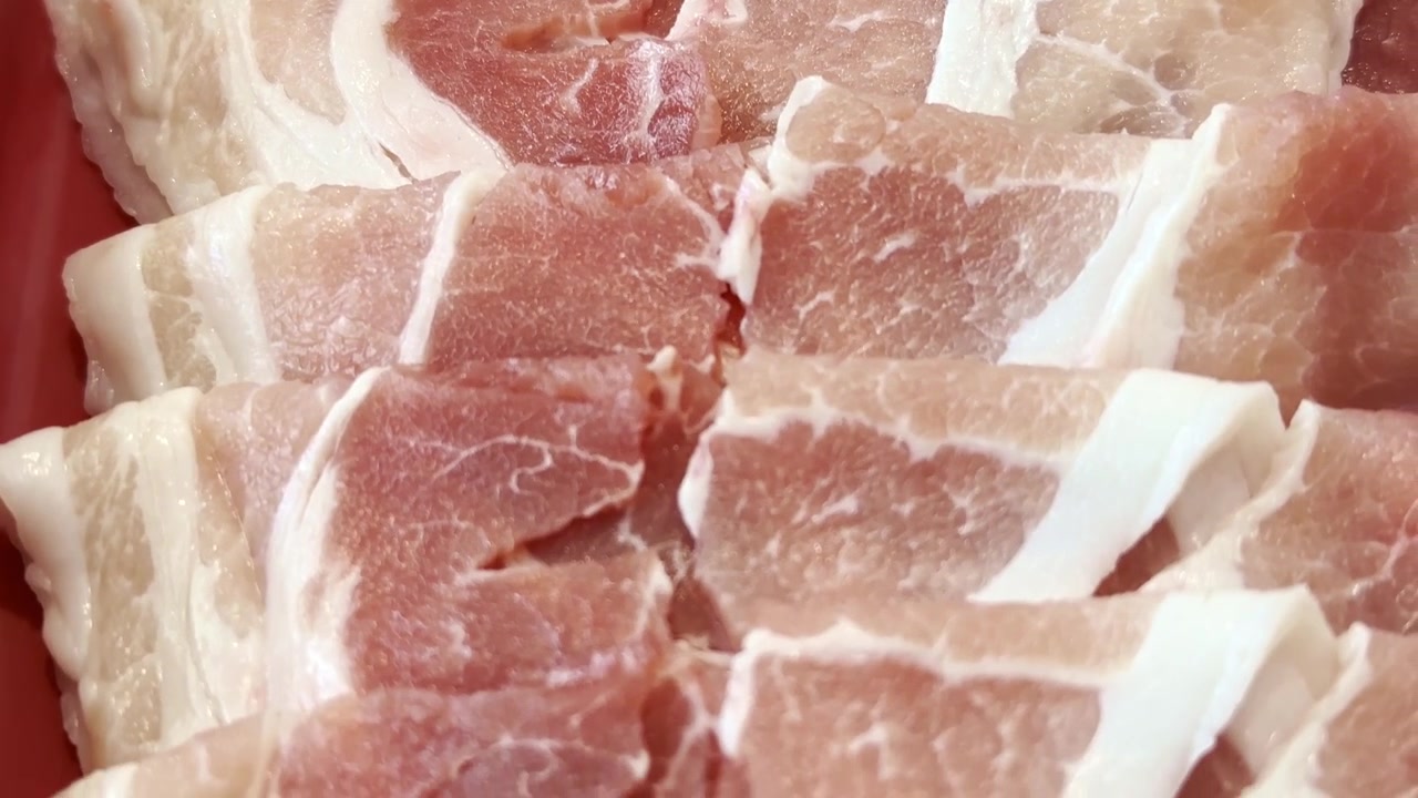 プレミアムな新鮮食材を使用し、すき焼きや鍋物用に準備された薄切り豚肉と牛肉が盛り付けられた皿のクローズアップ。