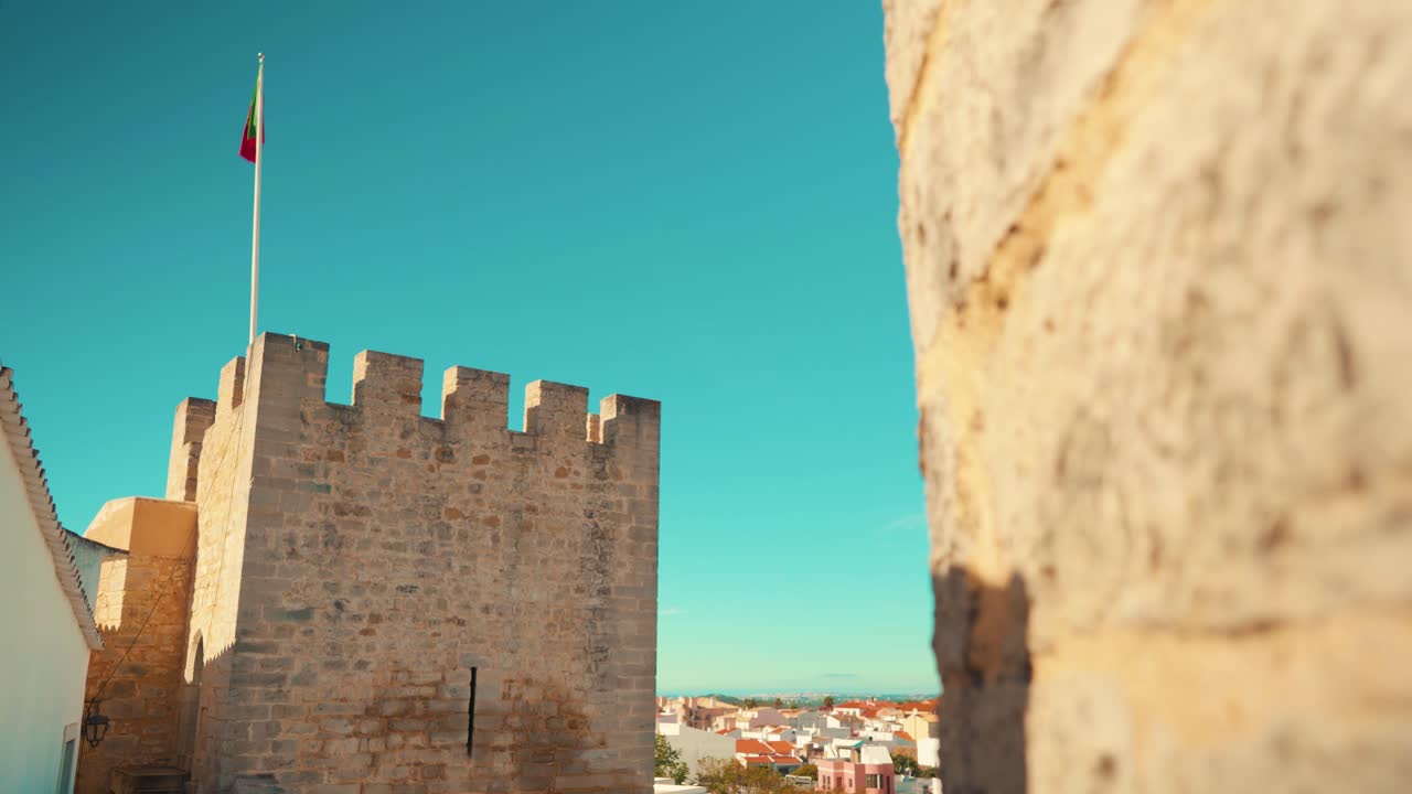 el muro de piedra de loule de portugal revela las almenas de la torre del castillo con la bandera en el movimiento de la cámara del camión bajo el cielo azul 4k
