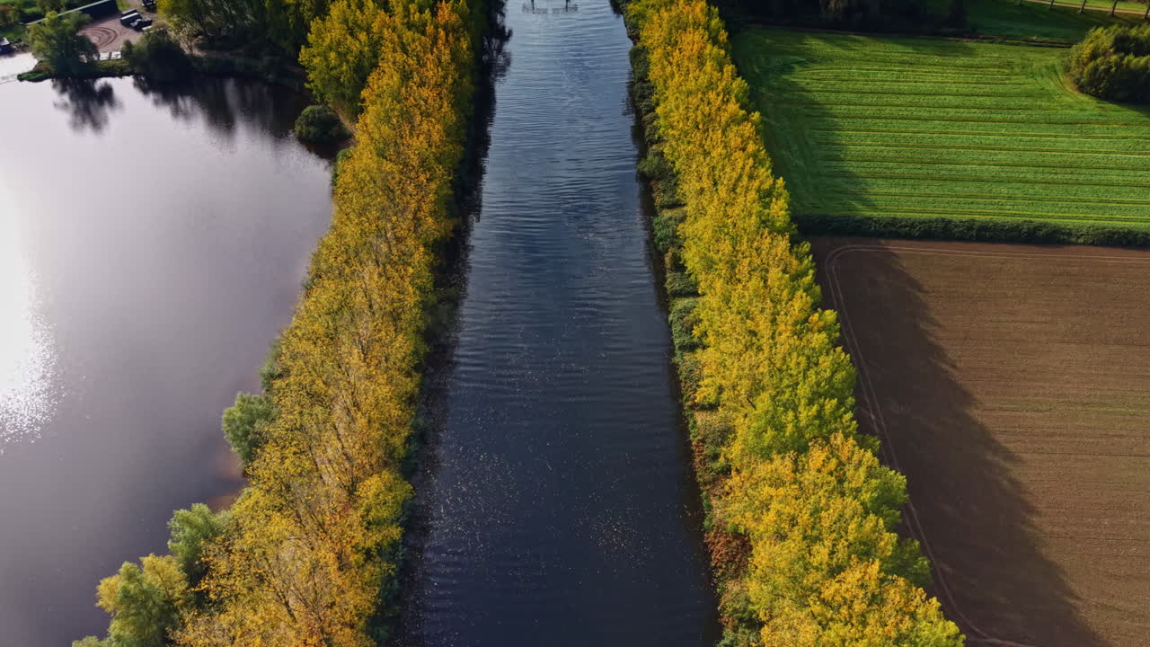 Une rivière calme serpente à travers les arbres d'automne et les champs près d'un paysage aquatique serein reflétant la beauté de la nature dans un cadre paisible