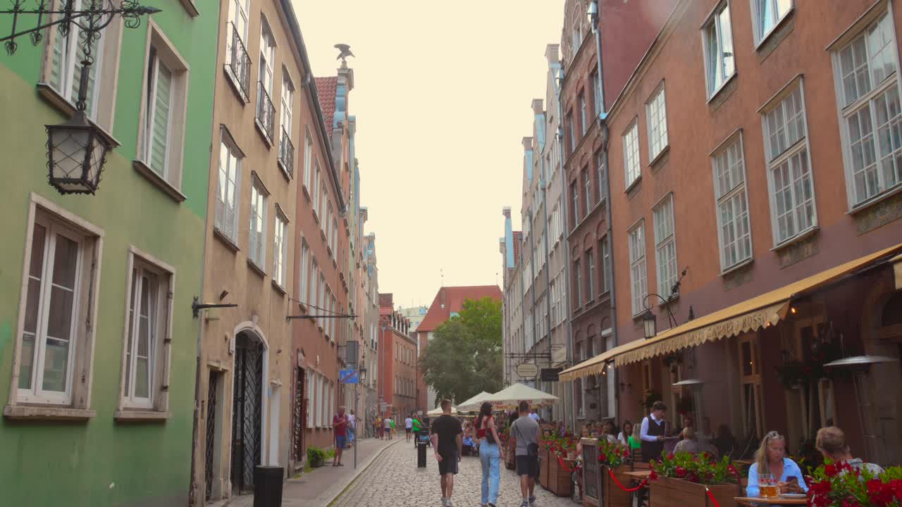 Street view of Gdansk Old Town with people walking, colorful buildings, and outdoor cafes