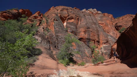 young woman walking in breathtaking landscape of utah desert, steep sandstone cliffs and eroded canyon, colorful scenery full frame slow motion