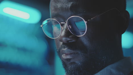 close-up of a man with glasses in a blue-lit environment
