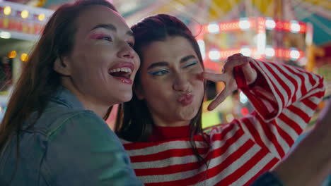 girls making funny selfie at funfair closeup. cheerful best friends in luna park