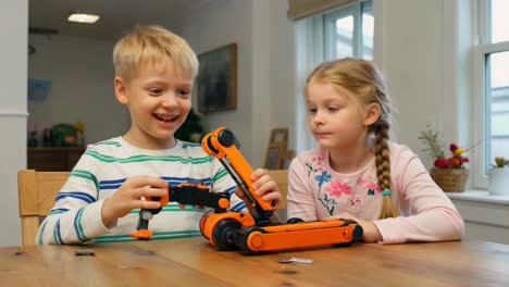 children playing with robotics toy on wooden table at home