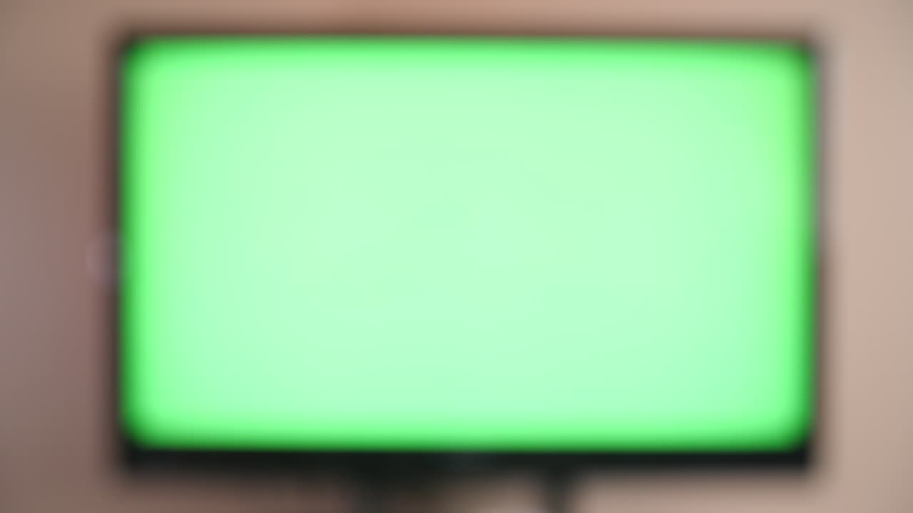 vista en primera persona de encender un televisor con un control remoto frente a un televisor moderno con pantalla verde y llave de croma
