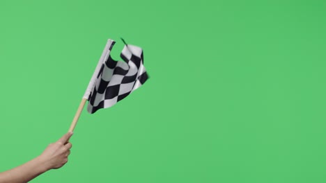 female hand holding and waving checkered race flag in slow motion against green screen background. victory, achievement, success, sport concept. silk black and white checkered flag finish start race