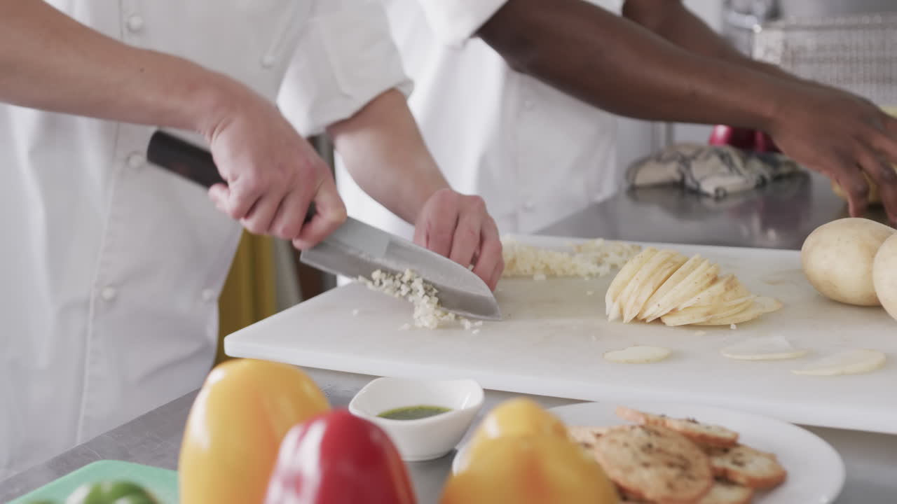 dos cocineros varones diversos cortando verduras en la cocina, en cámara lenta