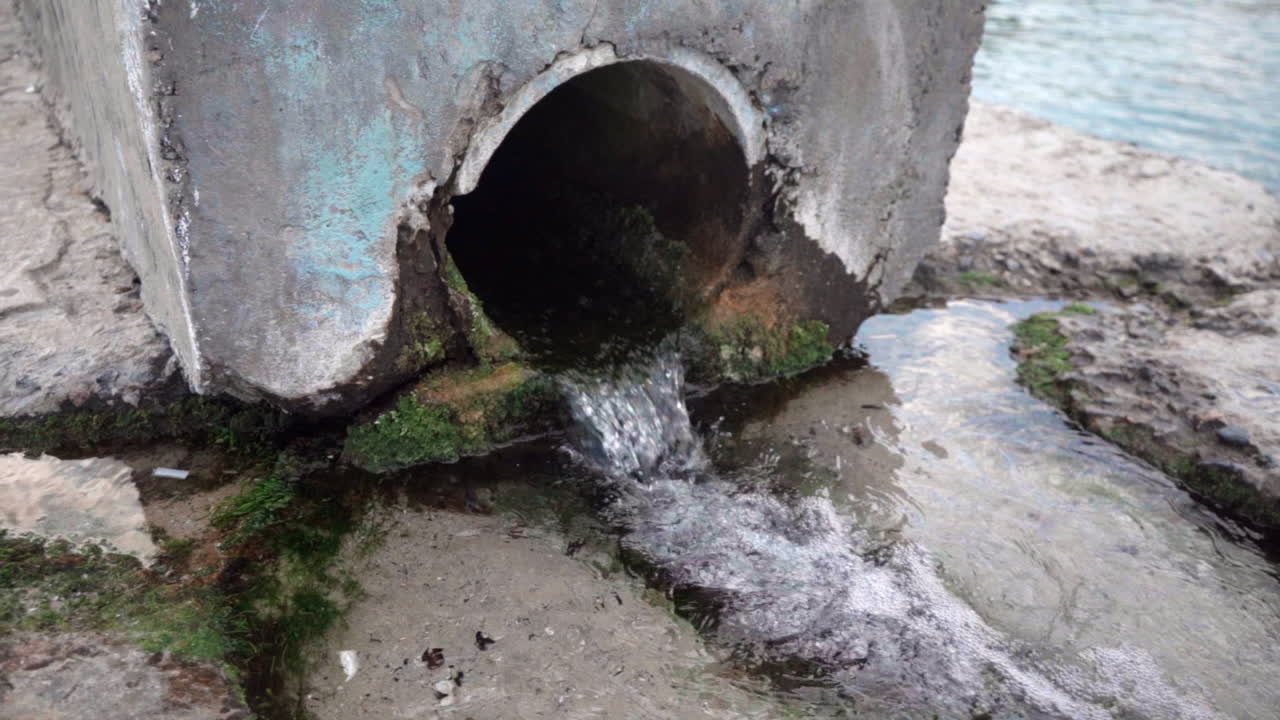 Water flowing out of old drainage pipe in the sea in slow motion