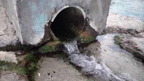 Water-flowing-out-of-old-drainage-pipe-in-the-sea-in-slow-motion