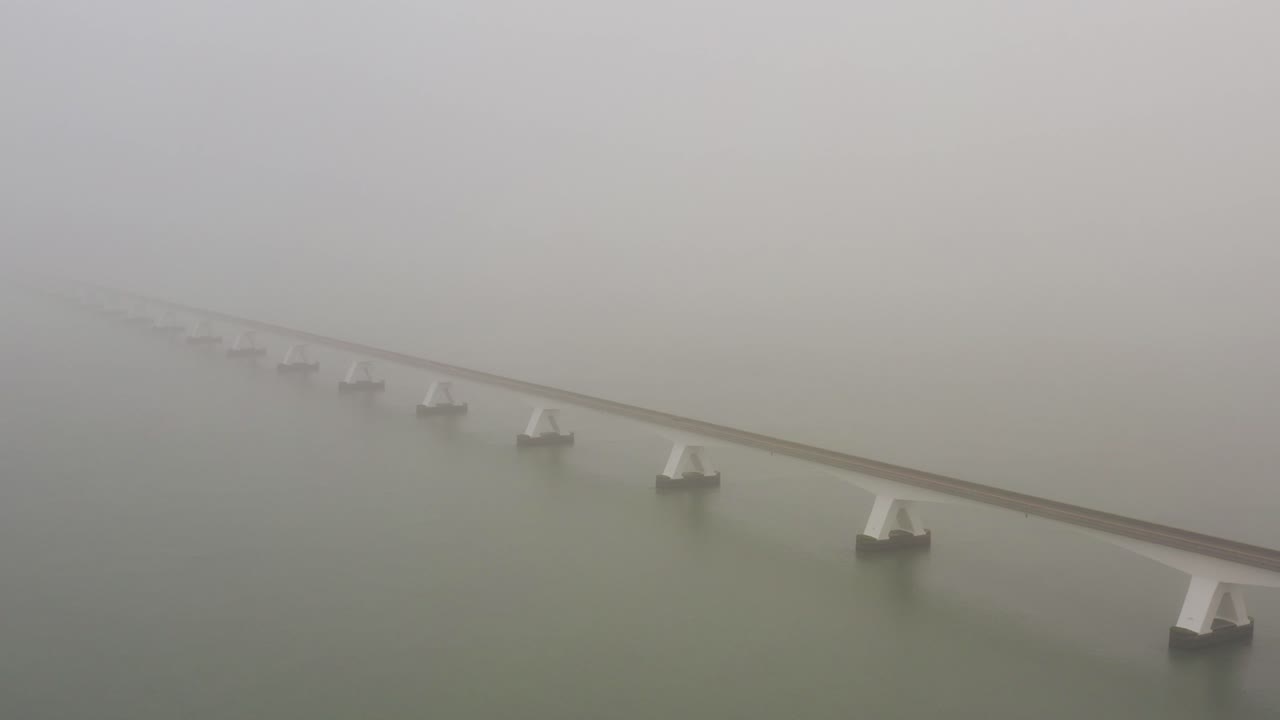 Aerial view of a long bridge crossing between islands during thick fog in the Netherlands.High angle