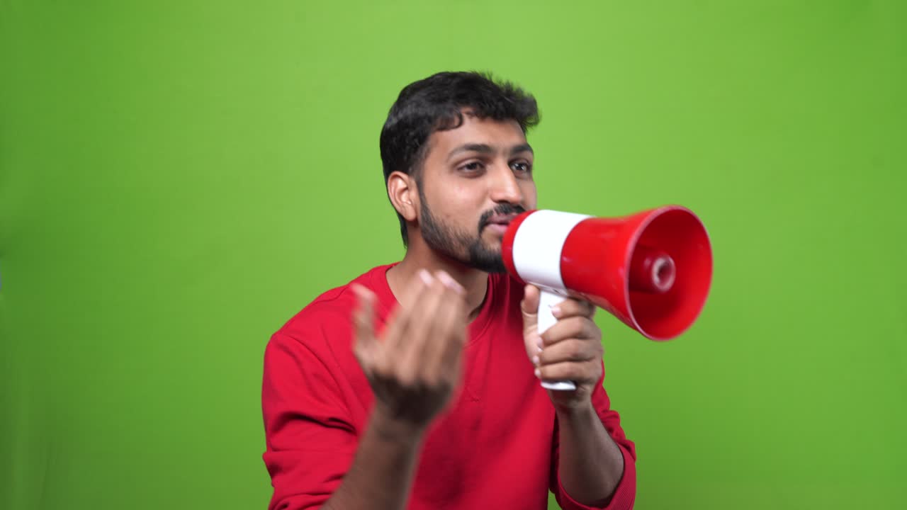 Indian man shouting with a megaphone over a green screen background