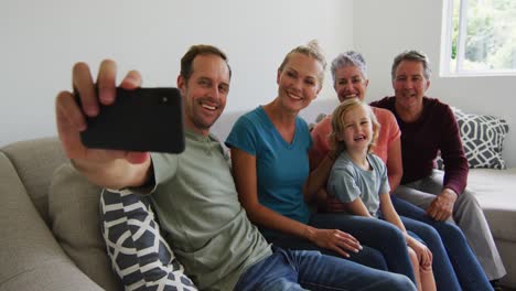 familia caucásica de tres generaciones tomando una selfie juntos con el teléfono inteligente en casa