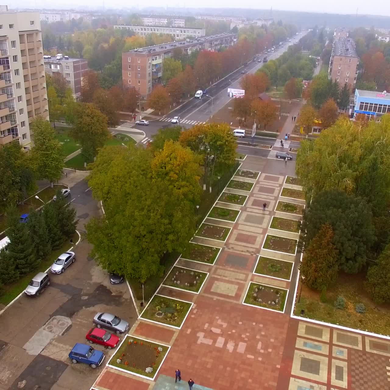 Area verde colorata in centro città. Strade ed edifici circondati da alberi. Sfondo di una giornata autunnale nuvolosa