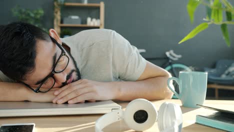 cinemagraph of young man in glasses sleeping on desktop at home relaxing after work