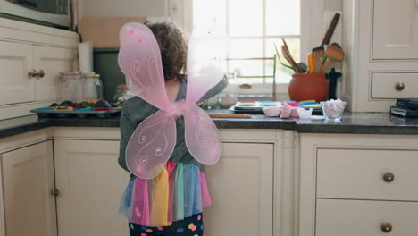 happy little boy baking in kitchen mixing ingredients for homemade chocolate cupcakes having fun preparing delicious treats wearing butterfly wings costume