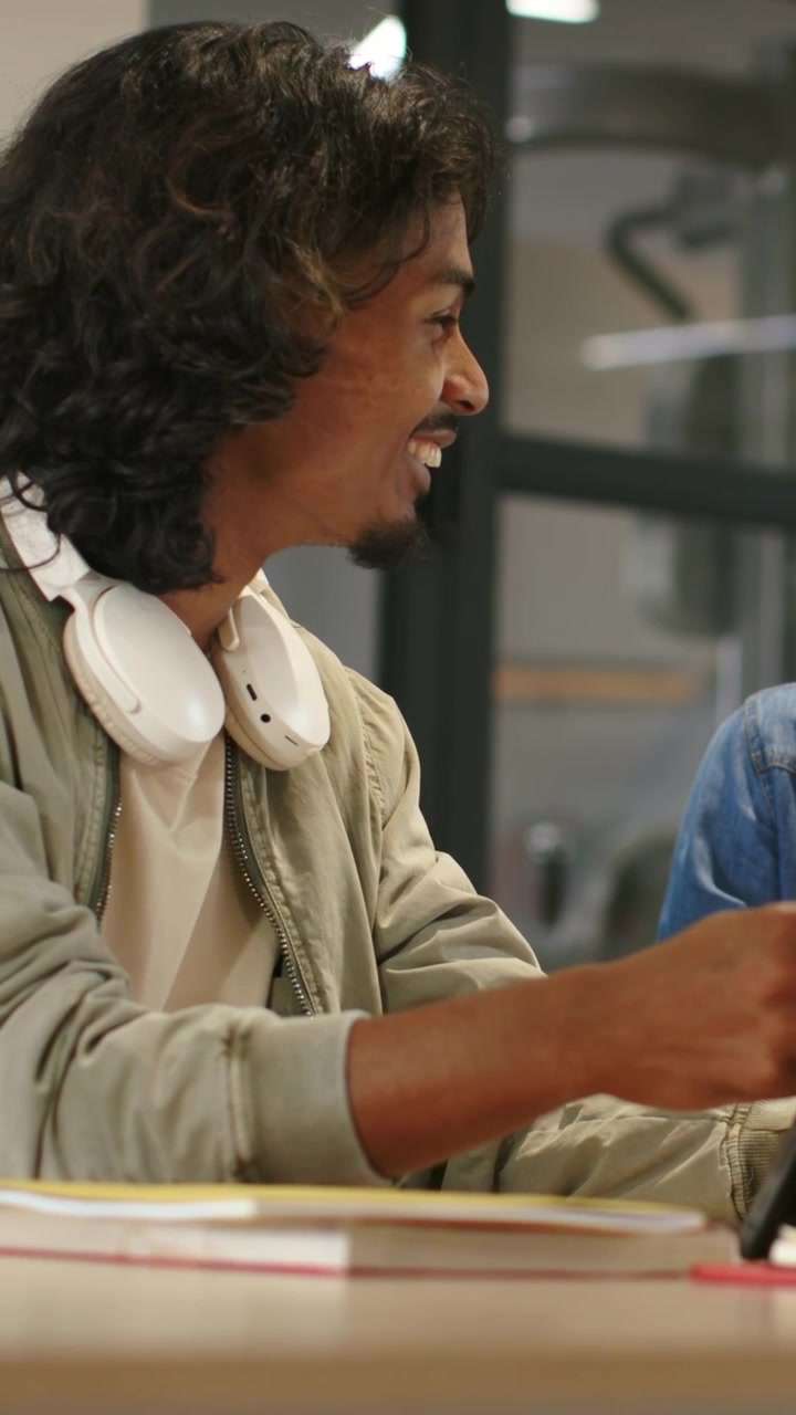 Vertikal video: Ser ledsager vise telefon, mand i jakke smiler ved skrivebord, holder headset