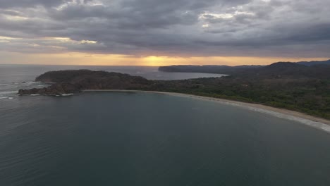 costa del océano pacífico de costa rica al atardecer con playa de arena de media luna, tiro aéreo