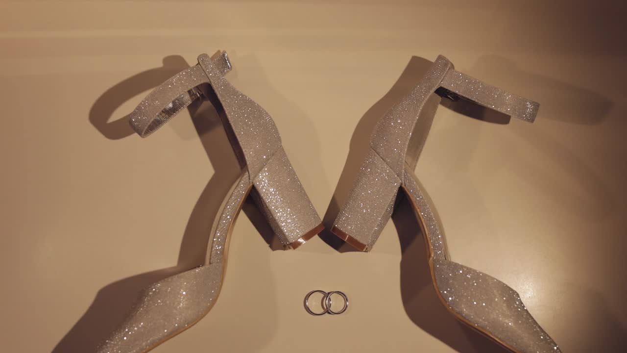 아름다운 크림색 저녁 신발을 입은 여성들이 바닥에 누워 두 개의 황금 결혼 반지와 함께 클로즈업