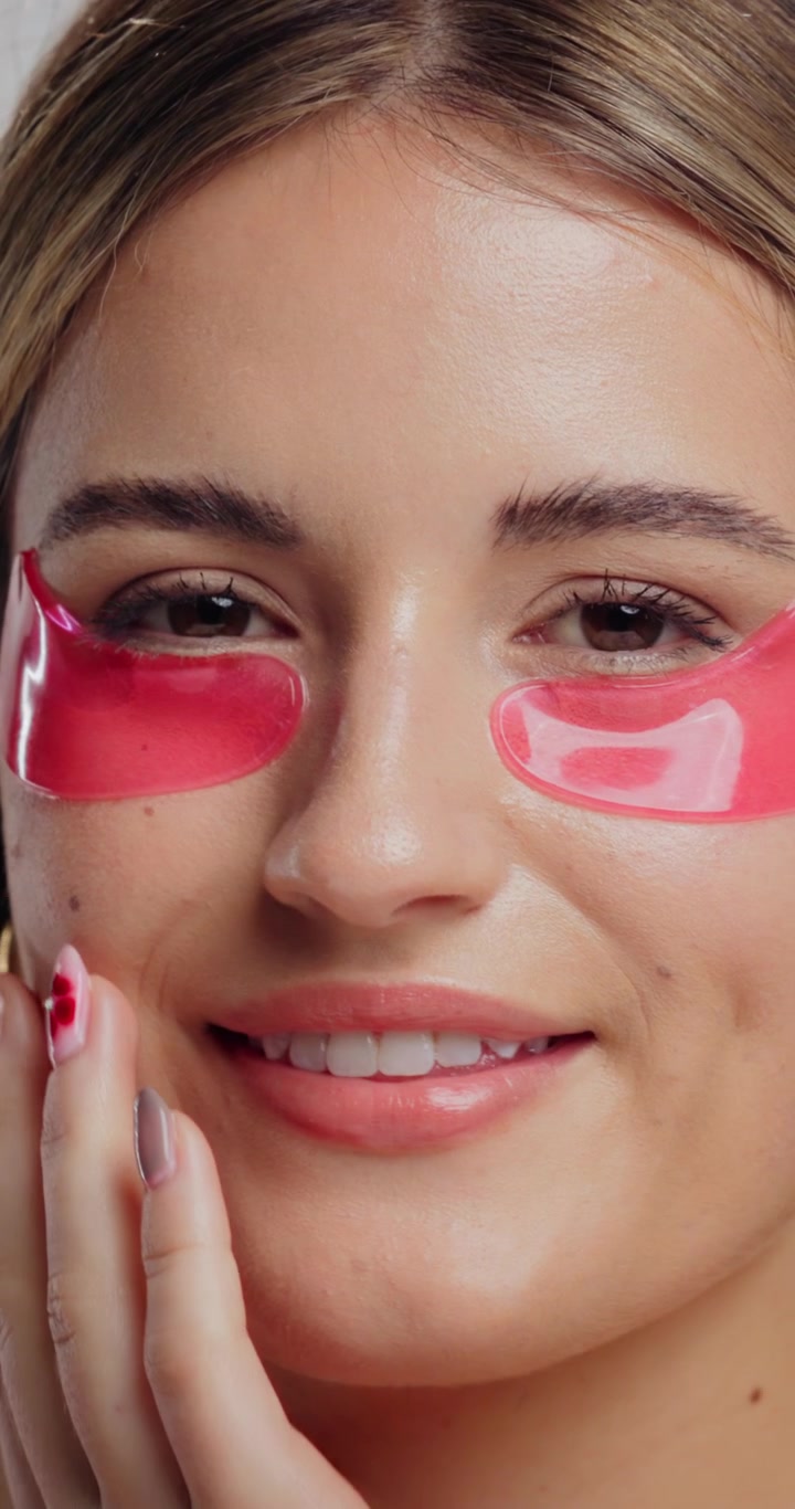 Giovane donna che applica cerottini rosa sotto gli occhi per la routine di skincare