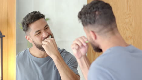 brushing teeth, man looking in mirror and smiling in bathroom