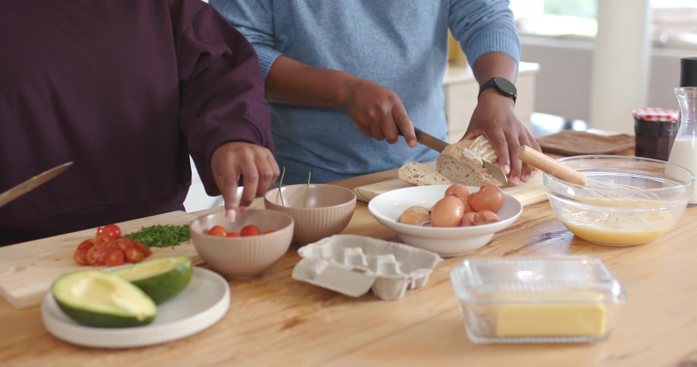 Afrikanisches Paar hackt und schneidet an der Kücheninsel, beginnt Rezeptvorbereitung mit Wellenschliffmesser