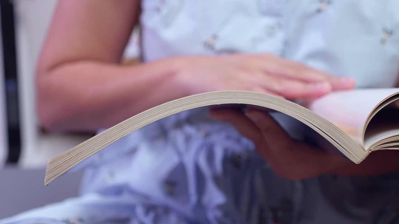 hojeando las páginas de un libro, una persona está leyendo y mirando las ilustraciones del libro en su mano