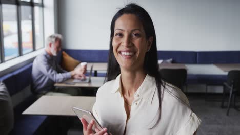 Portrait-of-mixed-race-businesswoman-standing-using-digital-tablet-in-office-