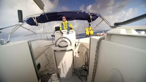 adult male behind sailboat wheel, sailing in tropical waters on sunny day, full frame