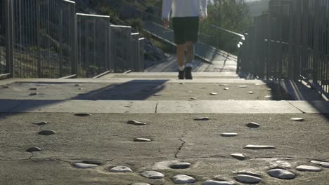 static shot of an unrecognizable woman walking away down stairs in hiking boots in an urban park with the sunset in the background