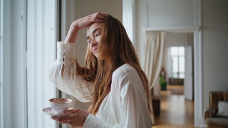 modelo sonriente tocando el cabello en el retrato de la habitación de la mañana. mujer feliz mirando la cámara