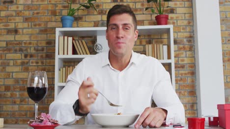 hombre caucásico haciendo una videollamada comiendo comida con vino y hablando