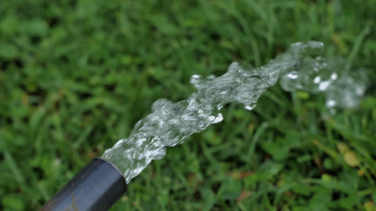 Necessary water sprays from a pipe over the grass of a garden